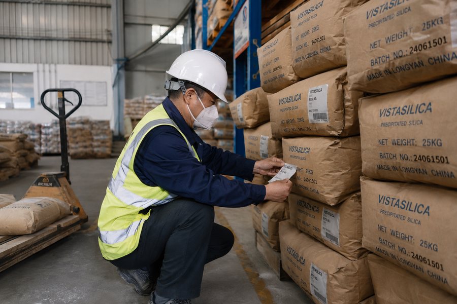Warehouse operator checking batch labels on 25 kg Censil Silica precipitated silica bags before dispatch.
